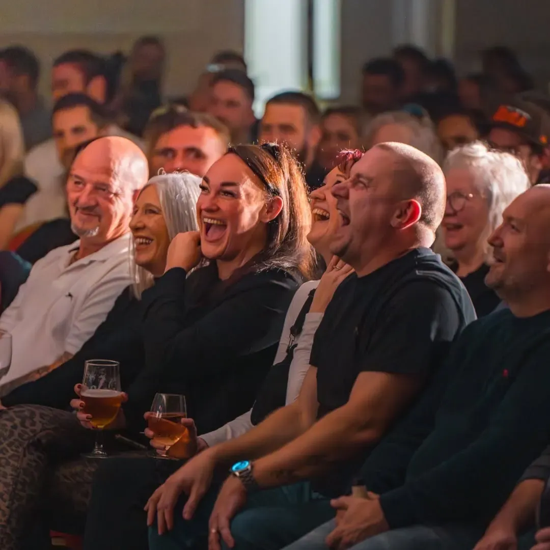 Audience members laughing together during a live comedy performance.
